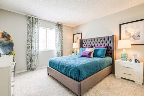 A bedroom with a large bed and a white nightstand.