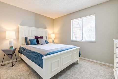 A bedroom with a bed, nightstand, and window.
