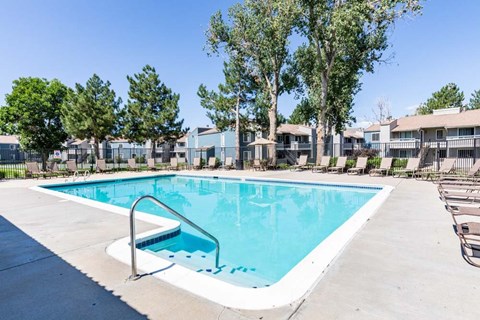 A swimming pool surrounded by trees and apartment buildings.