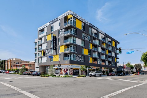 A multi-story building with a black and yellow facade is located on a street corner.