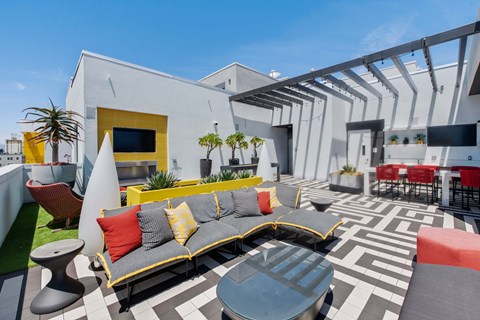 A white building with a yellow door and a grey couch.