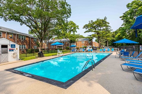 A large swimming pool surrounded by trees and chairs.