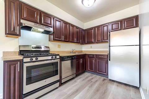 A kitchen with brown cabinets and a stainless steel refrigerator.