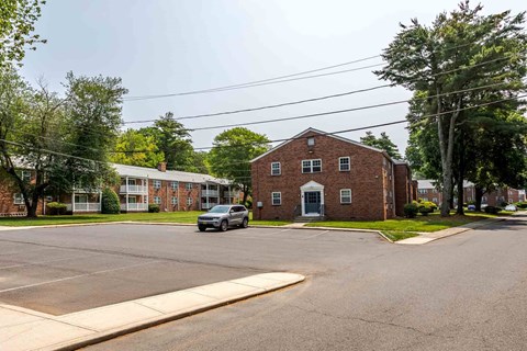 A car is parked in a parking lot in front of a brick building.