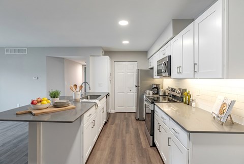 A modern kitchen with white cabinets and a wooden floor.