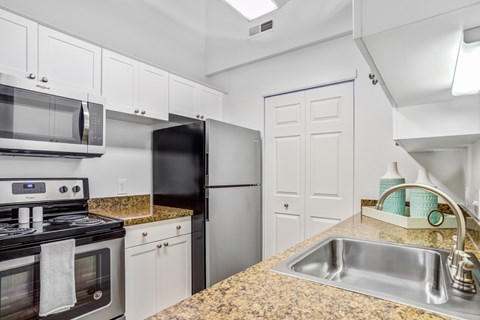 A kitchen with granite countertops and white cabinets.