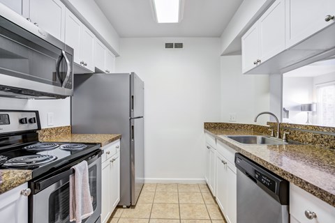 A kitchen with white cabinets and granite countertops.