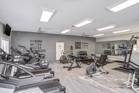 A gym with a variety of equipment including treadmills, weights, and exercise machines.