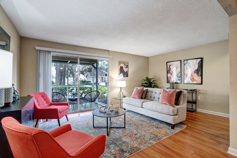 A living room with a grey couch, red chairs, and a rug.