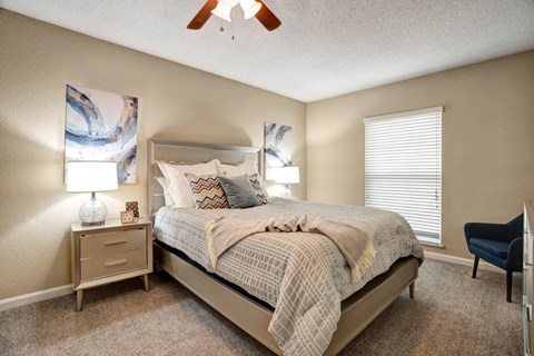 A bedroom with a bed, nightstands, and a ceiling fan.