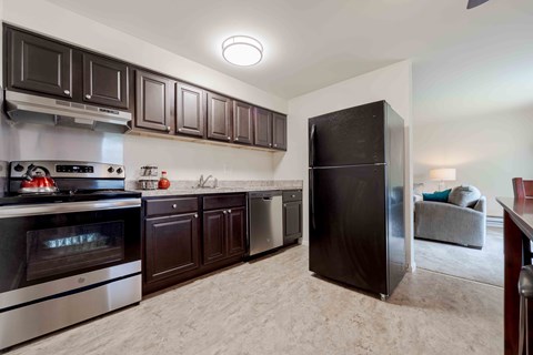 A kitchen with dark brown cabinets and a black refrigerator.