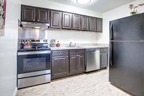 A kitchen with a black refrigerator and stainless steel appliances.