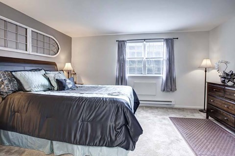 A bedroom with a large bed and a window with curtains.
