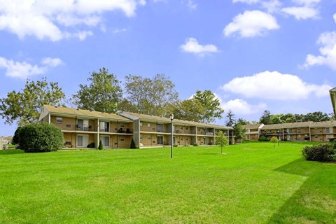 A row of apartment buildings with green lawns in front.