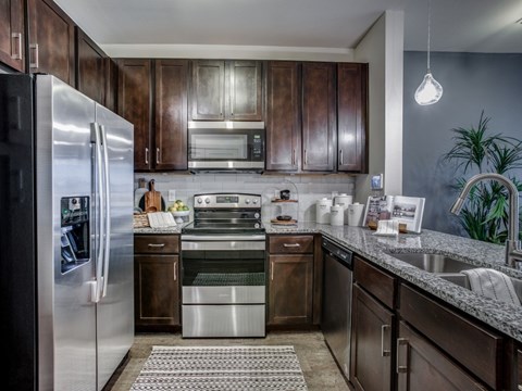 A modern kitchen with dark wood cabinets and stainless steel appliances.