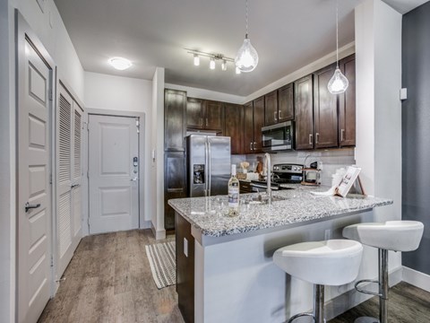 A kitchen with a white countertop and bar stools.