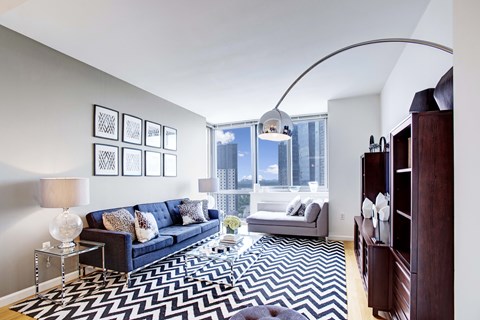 A living room with a blue couch and a black and white rug.