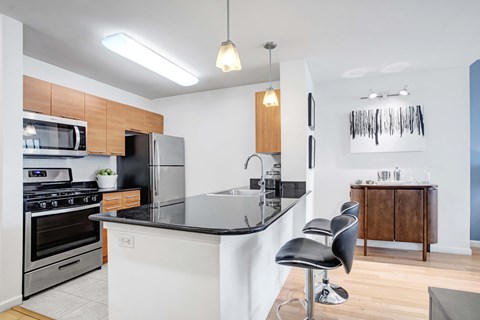 A modern kitchen with a black countertop and stainless steel appliances.