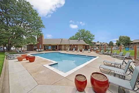 A pool surrounded by chairs and planters.