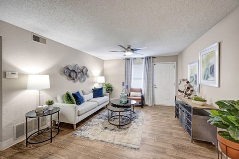 A living room with a white couch, a coffee table, and a ceiling fan.