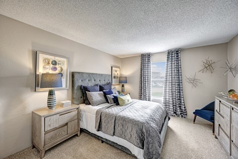 A bedroom with a bed, nightstand, and a painting on the wall.