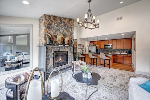 A modern living room with a stone fireplace and a large chandelier.