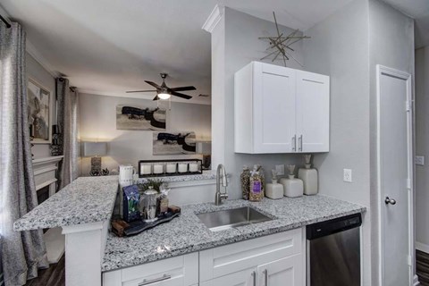 A kitchen with white cabinets and a granite countertop.