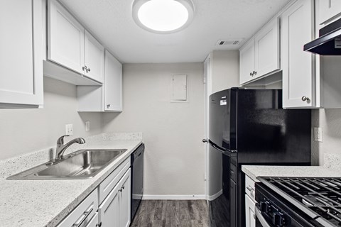 A kitchen with black appliances and white cabinets.