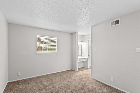 A room with a carpeted floor and a window with blinds.