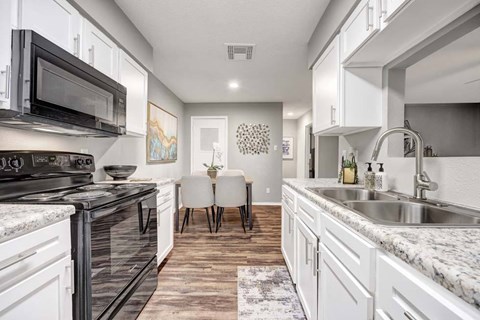 A kitchen with white cabinets and a black stove top oven.