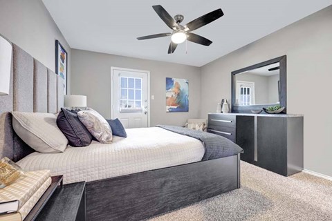 A bedroom with a large bed, a dresser, and a mirror.