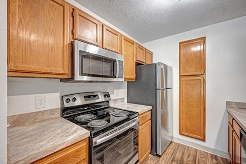 A kitchen with wooden cabinets and a stainless steel refrigerator.