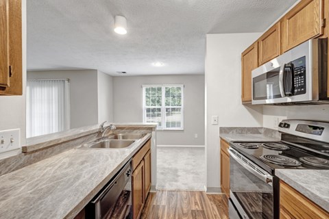 A kitchen with a stove, sink, and microwave.