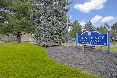 A sign for Stonehenge Apartments stands in front of a grassy area.