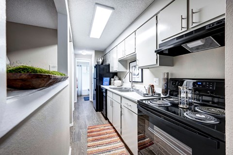 A kitchen with black appliances and white cabinets.