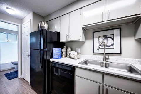A black fridge in a kitchen with a white counter top.