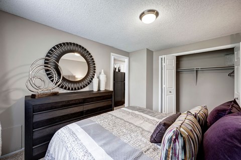 A bedroom with a bed, a mirror, and a dresser.