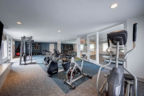 A spacious gym with a variety of equipment including treadmills, stationary bikes, and weight machines.