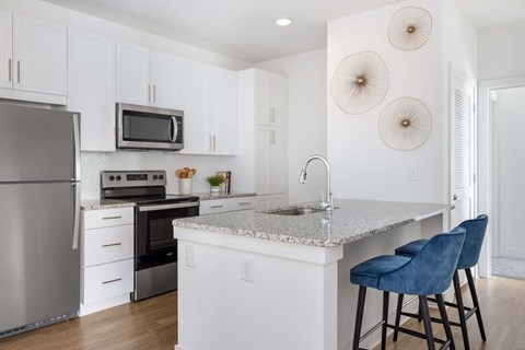 A kitchen with white cabinets and a granite countertop.