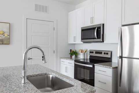 A kitchen with a sink, stove, and refrigerator.
