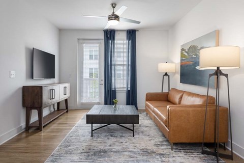 A living room with a brown couch, a coffee table, and a flat screen TV.