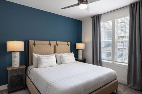 A bedroom with a large bed and two lamps.