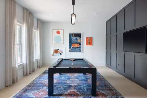 A pool table in a room with a rug and pictures on the wall.