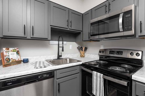 A kitchen with a stove, dishwasher, and microwave.