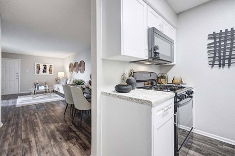 A kitchen with a white oven and a white dining table with chairs.