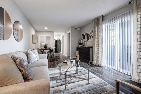 A modern living room with a grey sofa and a glass coffee table.