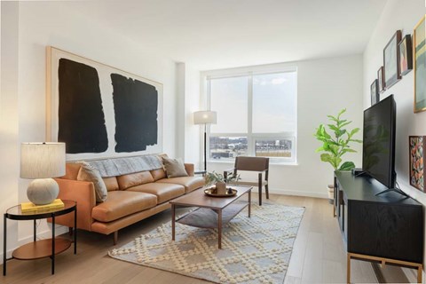 A living room with a brown leather couch, a coffee table, a lamp, and a large painting on the wall.