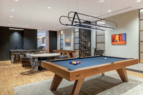 A pool table with a green cloth and a light hanging above it.