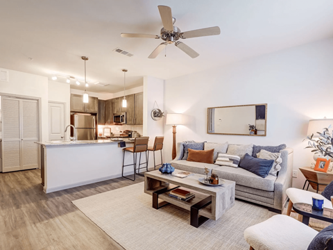 A modern living room with a kitchen area in the background.