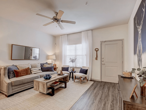 A living room with a couch, a coffee table, and a ceiling fan.